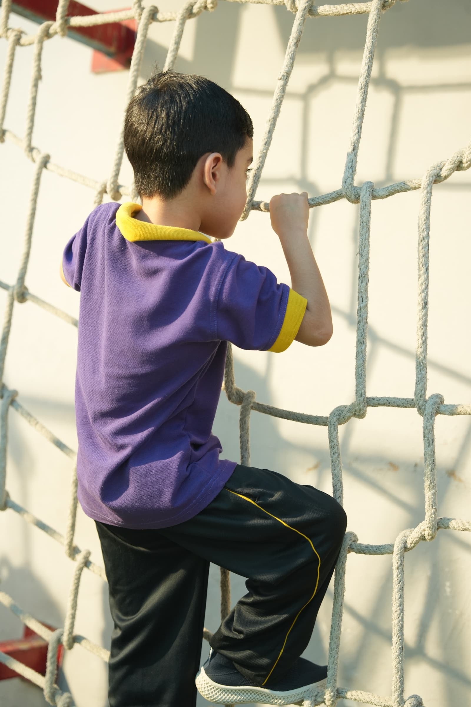 A child working their way up the rope climbing wall